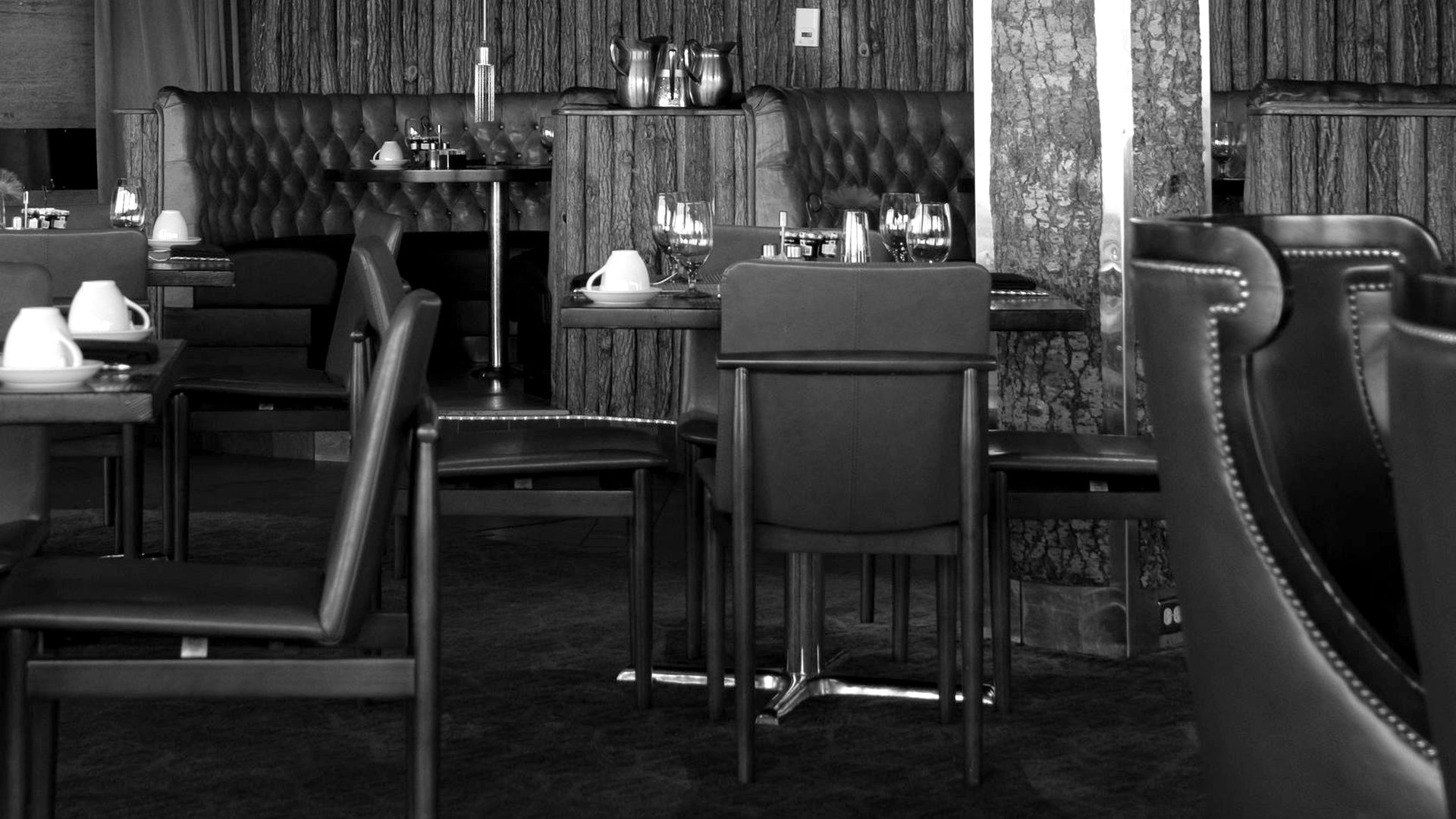 An empty hotel restaurant with laid tables, shot in grayscale