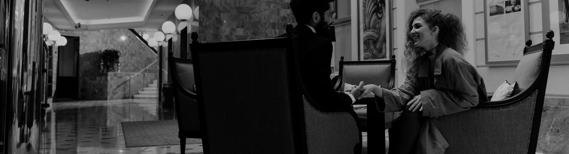 Two guests in armchairs in a hotel lobby