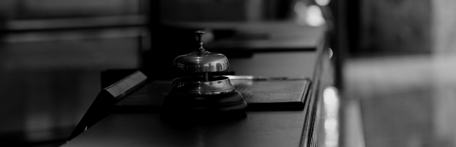 A brass bell on the reception counter, the lobby blurred behind it